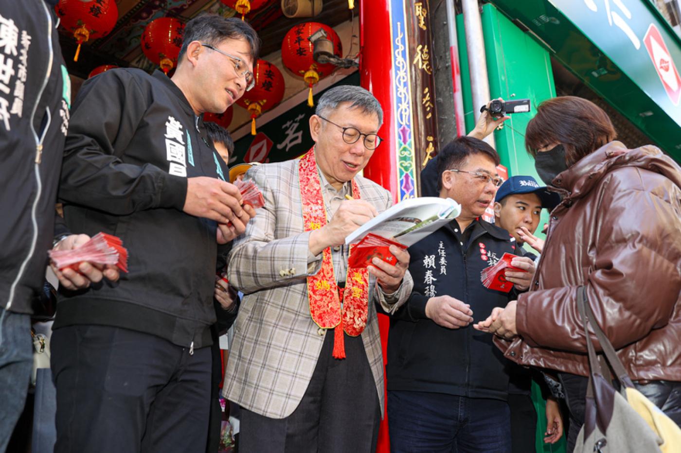 民眾黨主席柯文哲（中）12日上午與黨籍立委黃國昌（左）等人到新北板橋慈惠宮參香，並發放新春紅包給民眾，有支持者特別帶著書到場請柯文哲簽名。中央社