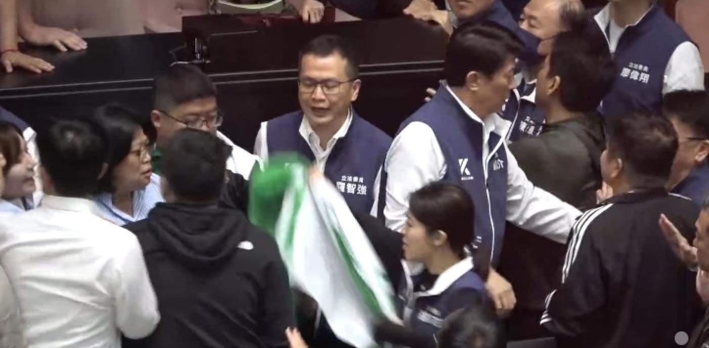 徐巧芯包裡拿出民進黨旗，折成「長條狀」，試圖捆在王美惠的脖子上。翻攝蔡易餘臉書