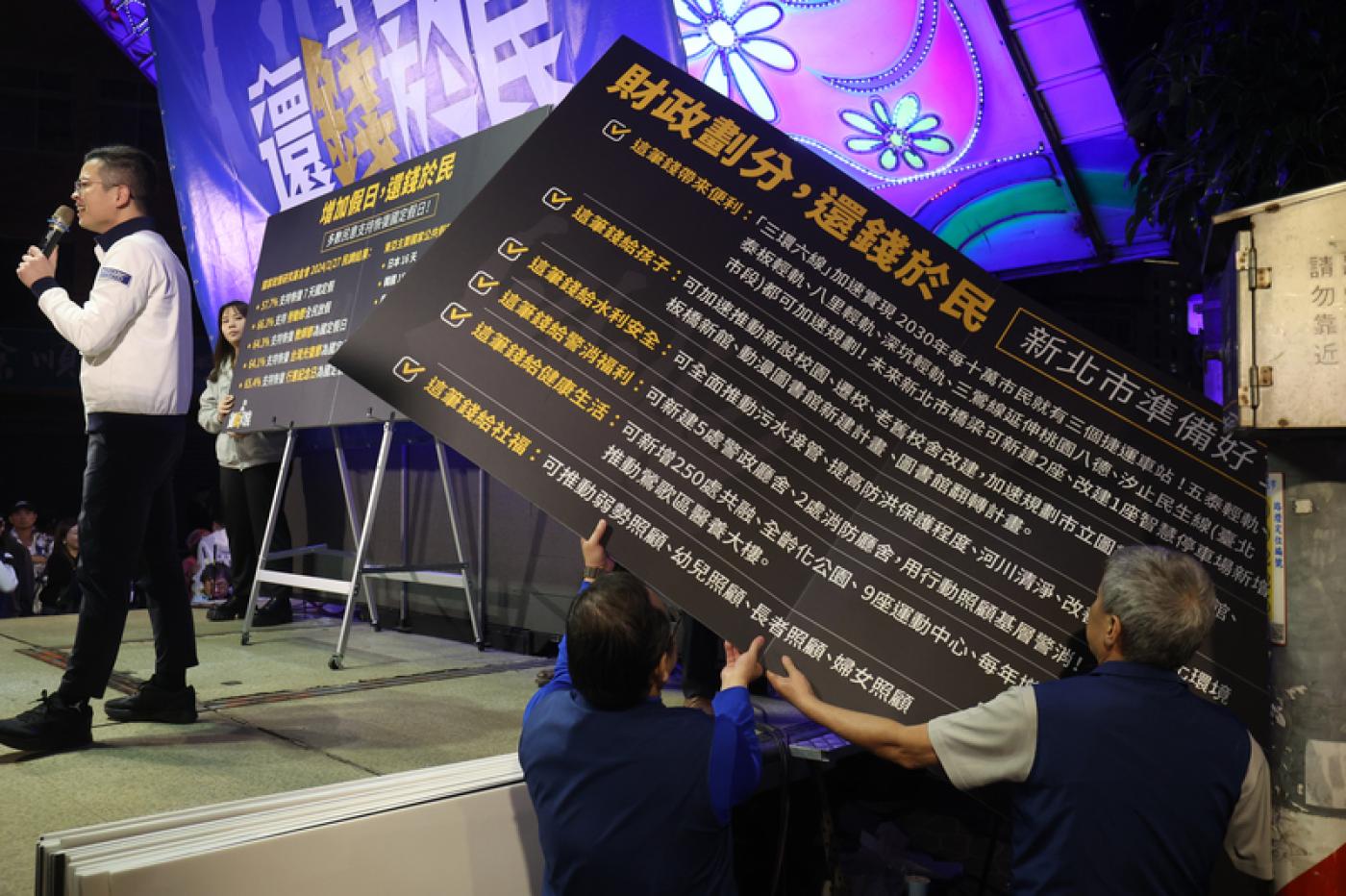 桃園市議員凌濤（左）昨日在新北市板橋登台宣講，搭配背板向群眾說明國民黨政策面向，不少民眾到場參與。 中央社