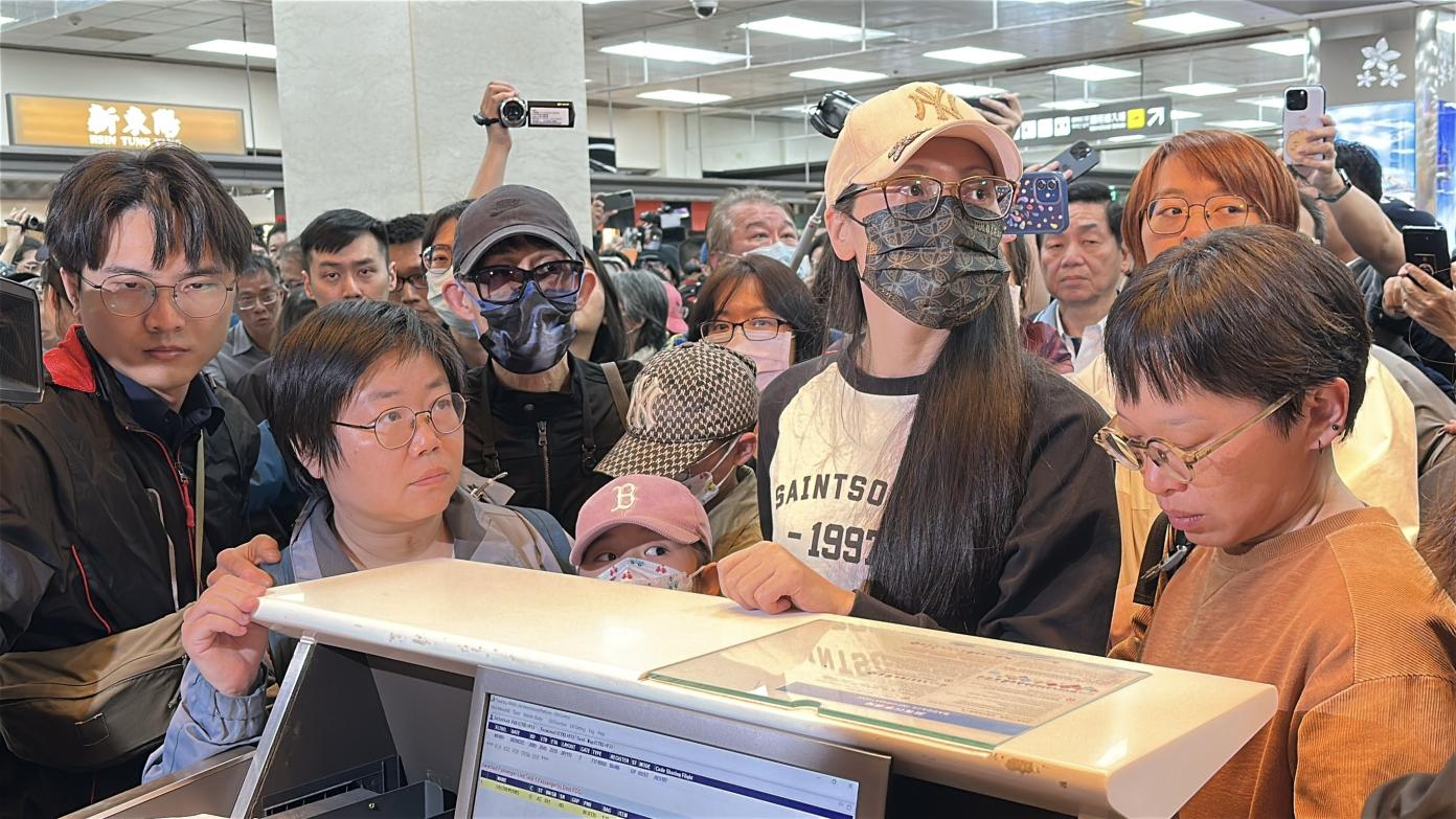 亞亞（右二）偕家人晚間現身松山機場，遭大批媒體包圍。林啟弘攝