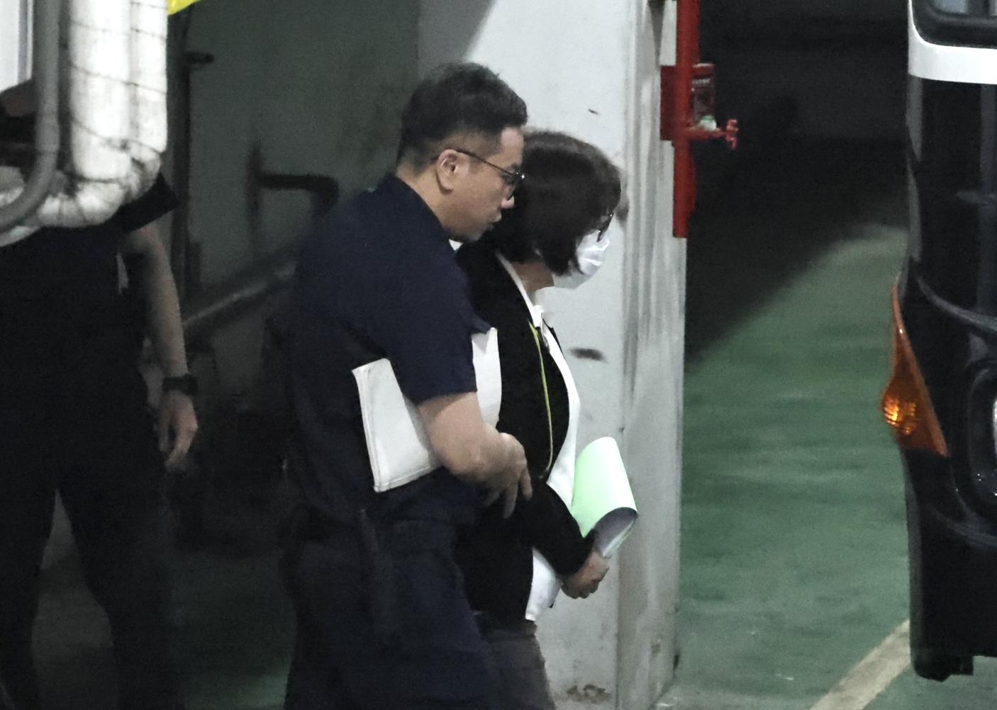 黃呂錦茹（右）用卷宗遮住手銬步上囚車。林啟弘攝