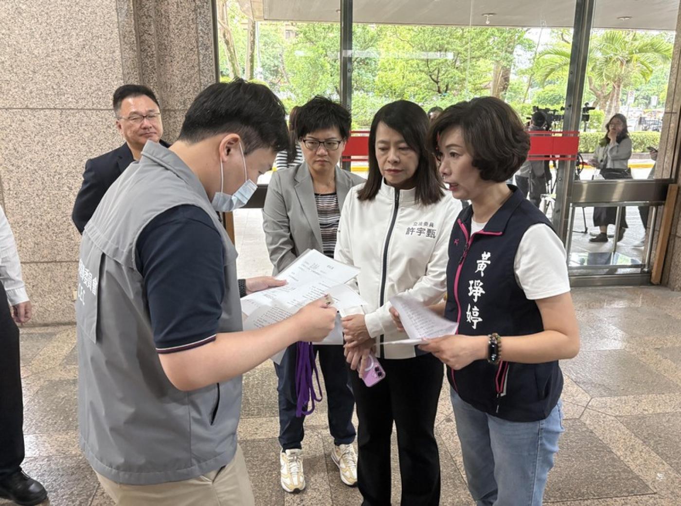 國民黨宜蘭縣議員黃琤婷（右1）25日與國民黨立委許宇甄（右2）代表罷免民進黨立委陳俊宇團體，赴中選會領取二階連署格式，中選會人員（左1）出面處理。中央社
