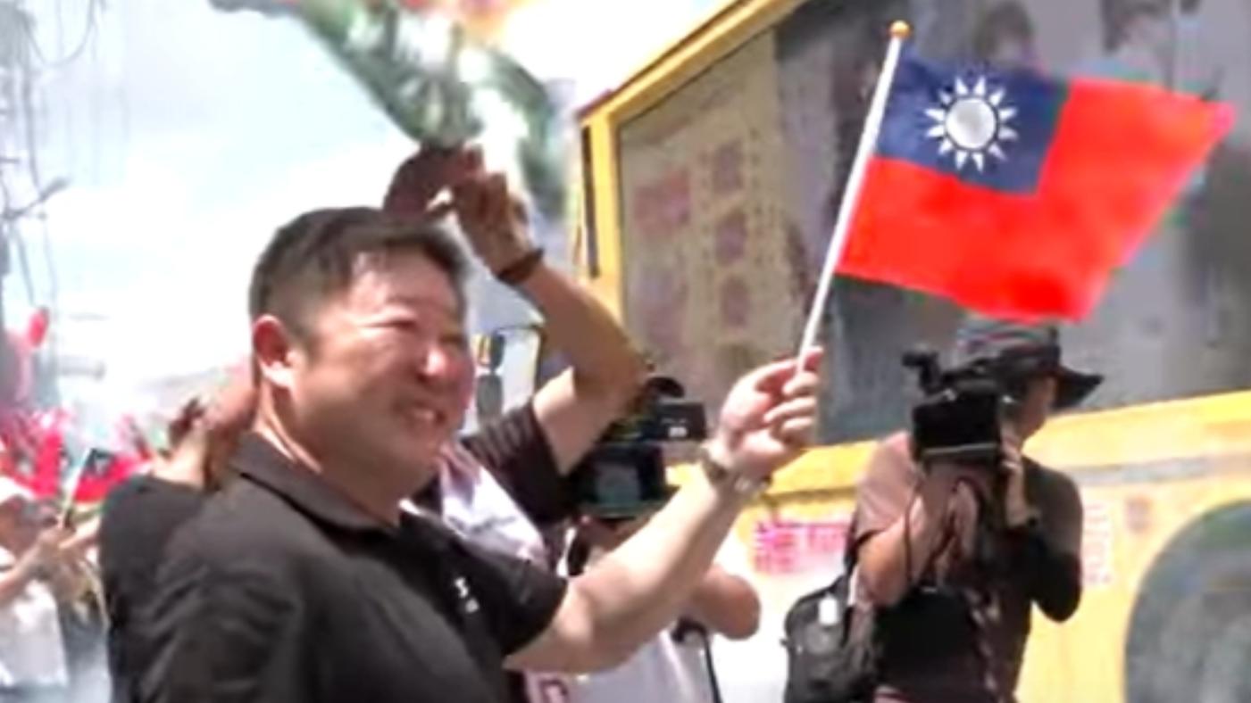 張峻率上百位支持者揮舞國旗，放鞭炮相迎「護國大遶境」車隊。翻攝畫面
