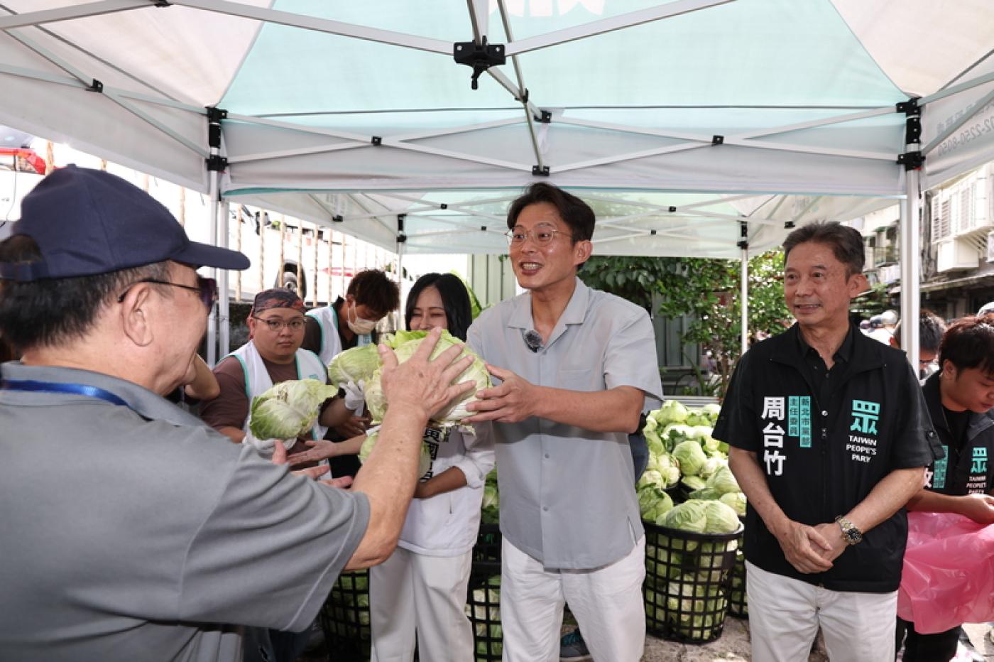 民眾黨主席黃國昌（中，灰衣者）6日上午出席「民眾加菜啦」汐止場活動，現場發送新鮮的高麗菜，為民眾加菜。 中央社